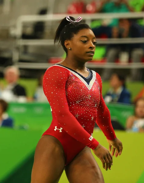 "Simone Biles performing a high-flying gymnastic routine during a competition, showcasing her strength and grace as she prepares for the 2024 Olympics."